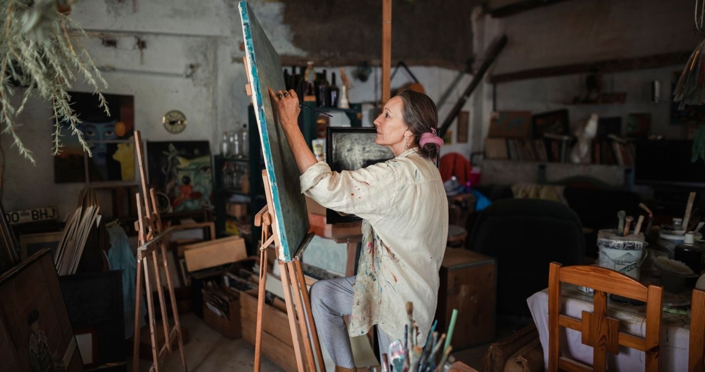 A female artist painting on a canvas in her Vermont art studio