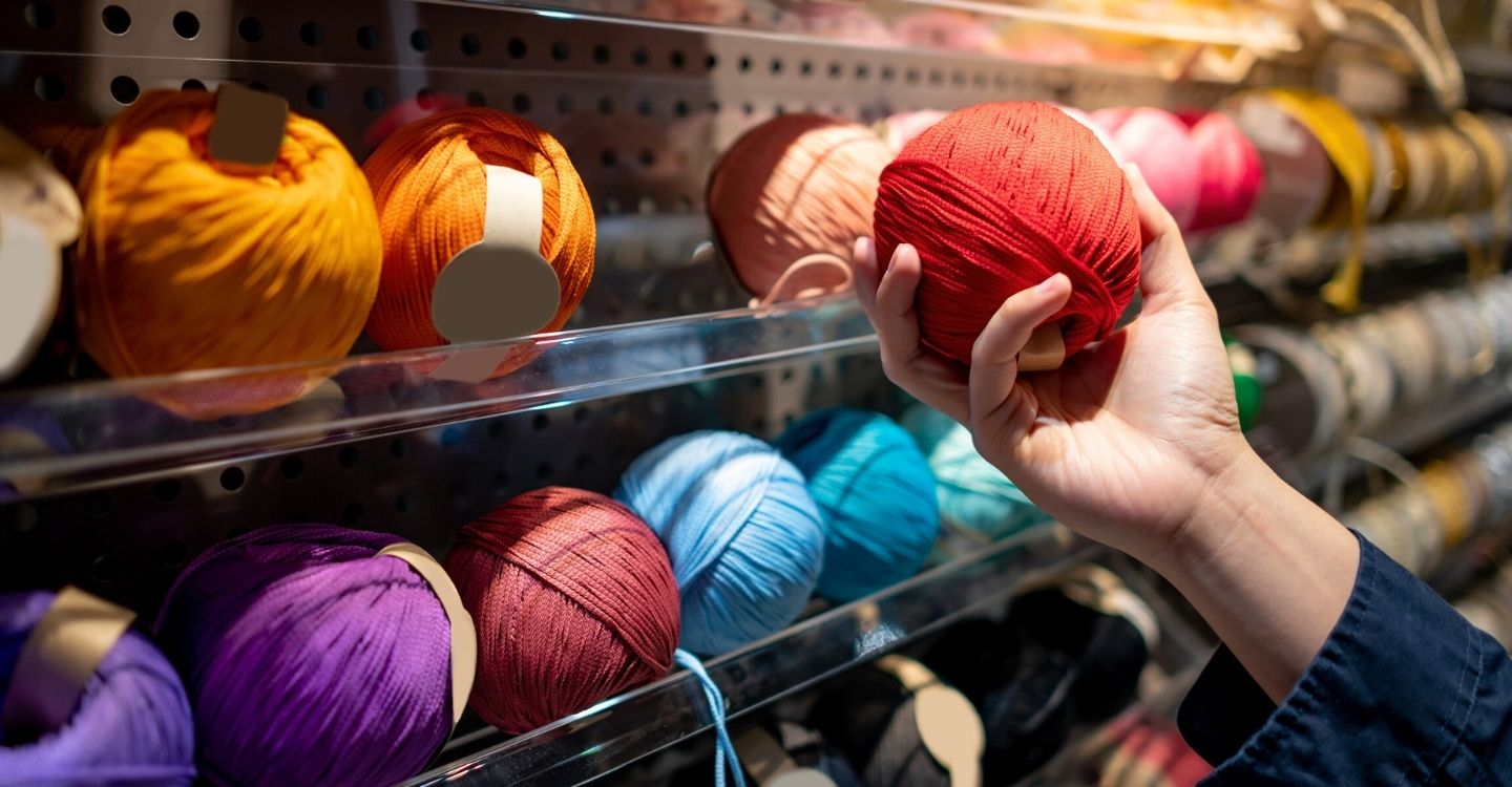 A hand picking up a skein of yarn from a shelf during the The Great Northern Yarn Haul in Vermont